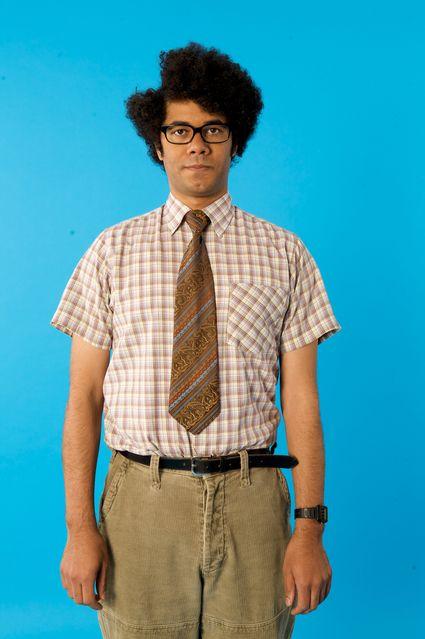 Moss from the IT Crowd standing awkwardly in a nerdy outfit
